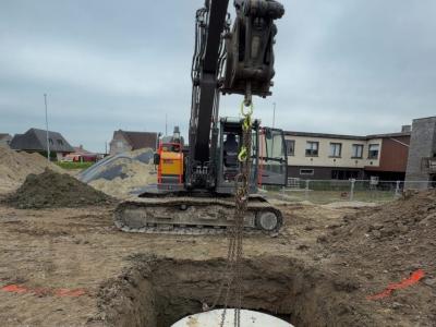 Inlaten van regenput op werf te Lede met rupskraan