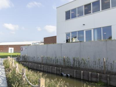Afgewerkte wadi met berlinerwand in hardhout met groenaanleg in Kruisem