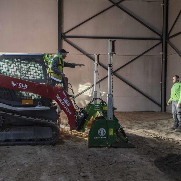 Rupslader met nivelleerblad maakt de grondvlak binnen in de loods